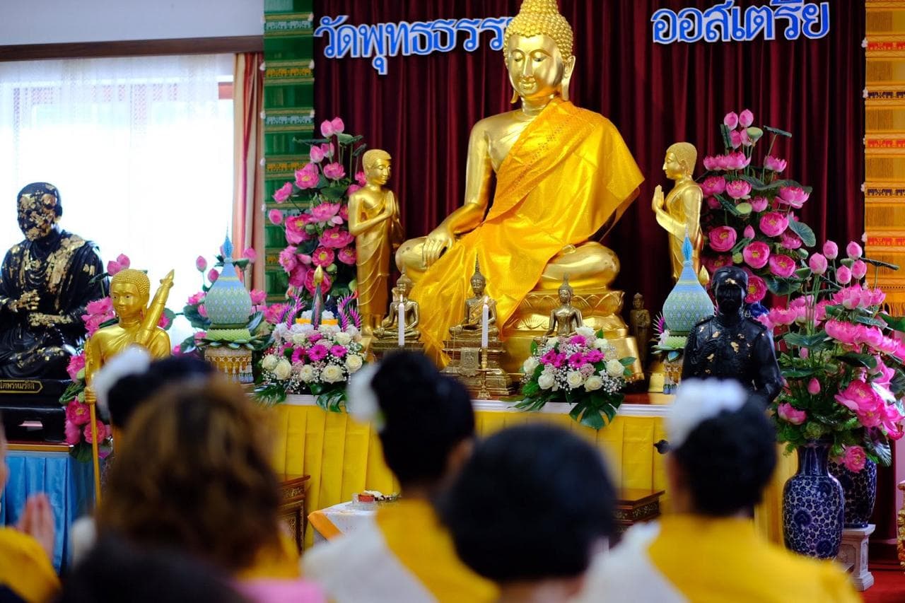 Goldener Buddha-Schrein des WAT Buddhadham Tempels mit Kerzenlicht und Blumenkränzen